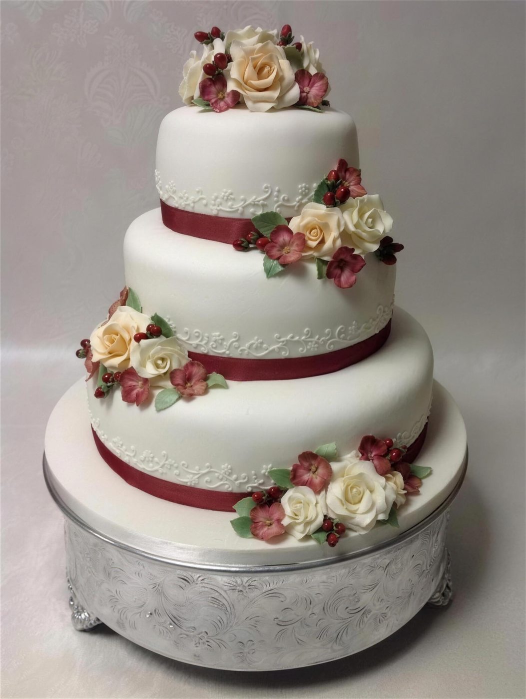 A classic ivory tiered wedding cake finished by hand with sugar roses