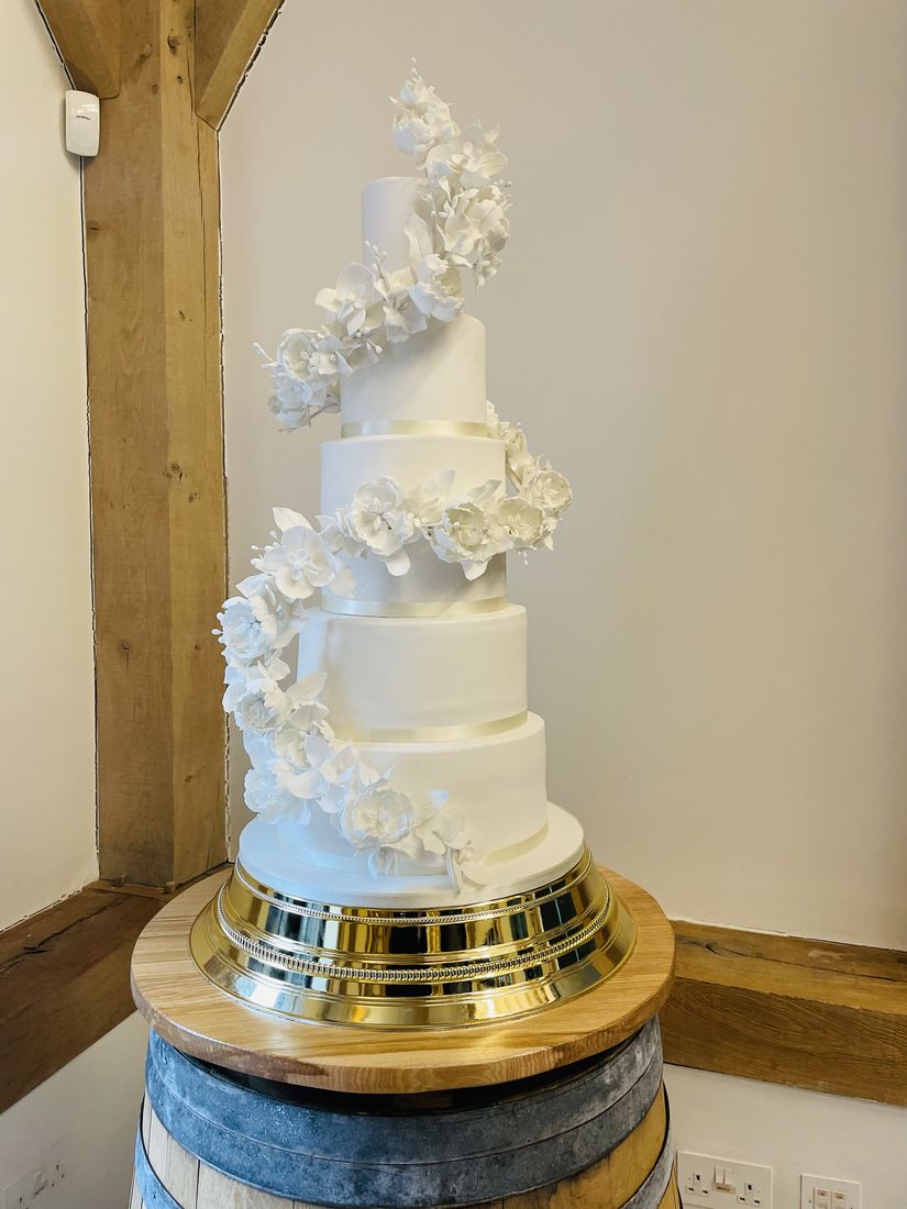 Tall white wedding cake with a cascading spiral of sugar flowers