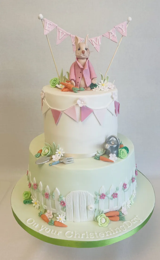 Beatrix Potter garden christening cake with a bunny topper, bunting, garden gate and sugar carrots by Catherine Scott