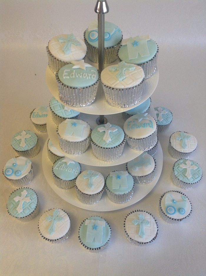 Tower of pale blue christening cupcakes with baby themed sugar toppers on a stand